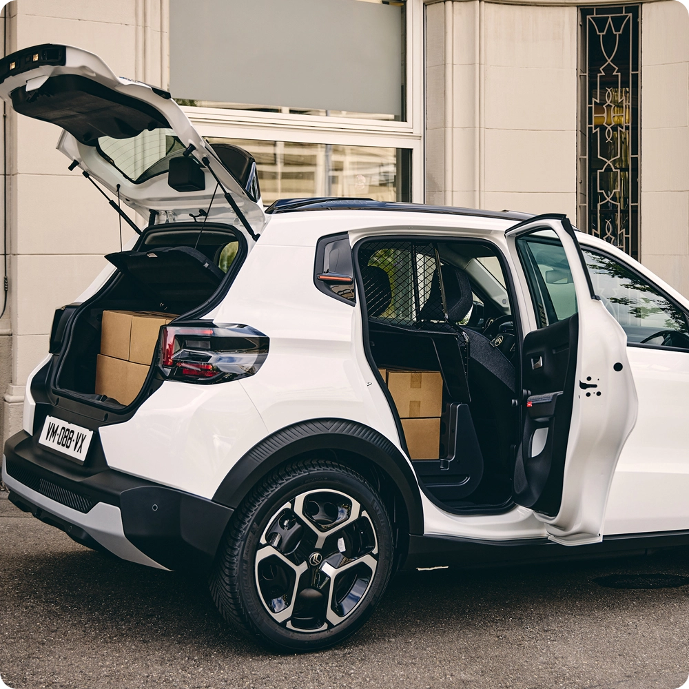 Dreiviertel-Heckansicht des Citroën ë-C3 Van mit geöffneter Heckklappe und Beifahrertür, die Ladezugänglichkeit, vielseitige Ladelösungen und SUV-inspiriertes Styling hervorhebt.