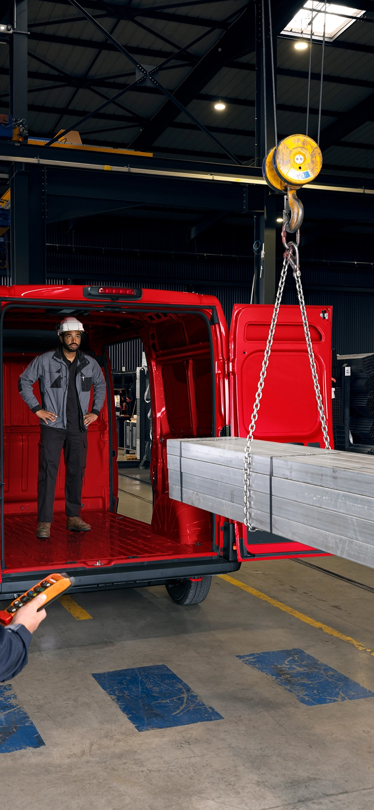 Rückansicht eines roten Citroën Jumper, der in einer Industrieumgebung mit Metallträgern beladen wird, wobei das große Ladevolumen und die hohe Belastbarkeit deutlich werden.