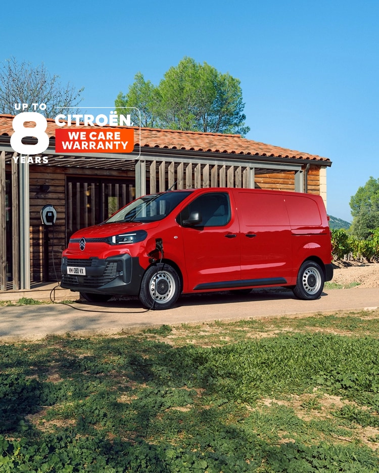 Seitenansicht eines roten Citroën ë-Jumpy beim Laden vor einem Gebäude, zeigt modernes Elektro-Design, Alltagstauglichkeit, Konnektivität und professionelles Auftreten.