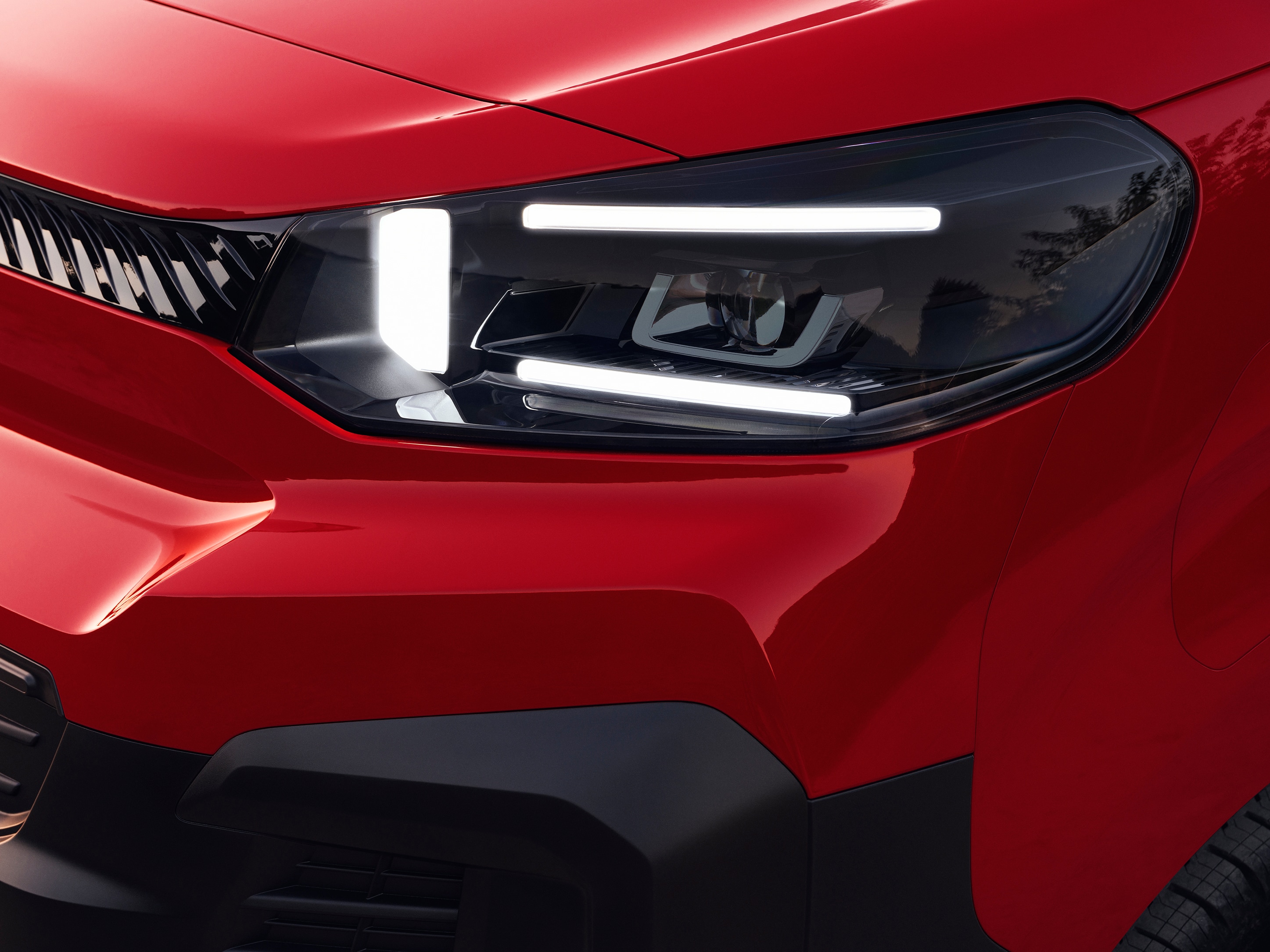 Nahaufnahme des vorderen Scheinwerfers eines roten Citroën Jumpy, zeigt modernes Lichtdesign und robustes Styling.