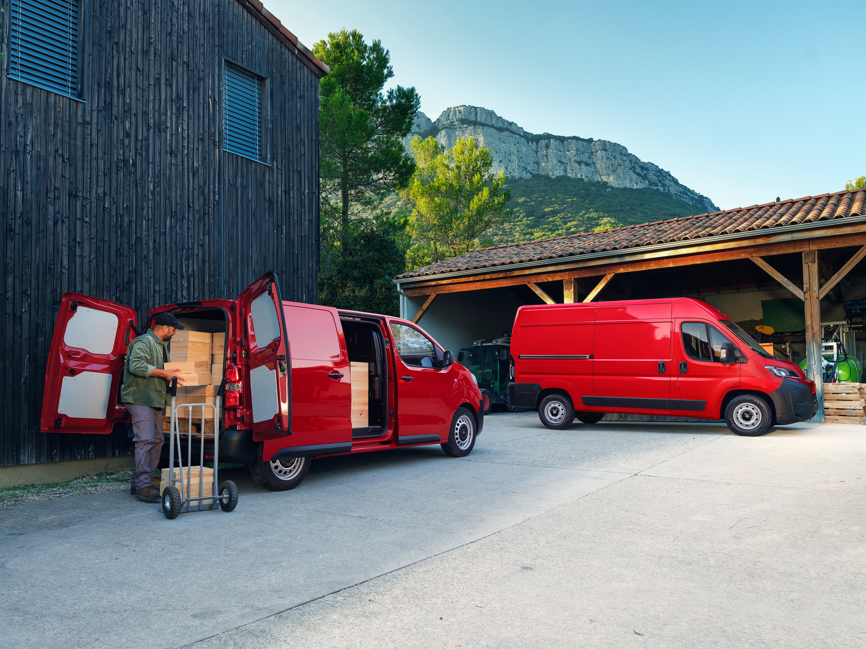 Hintere Dreiviertel-Außenansicht von zwei roten Citroën Jumpy während des Beladens, zeigt vielseitige Konfigurationen, großes Ladevolumen und Eignung für alltägliche professionelle Tätigkeiten.