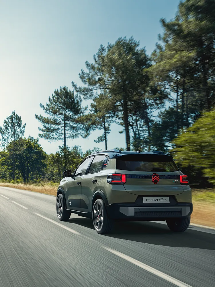 Heck-Dreiviertelansicht des Citroën ë-C3 Outdoor mit LED-Rückleuchten zeigt den kompakten SUV mit Advanced Comfort auf offener Straße