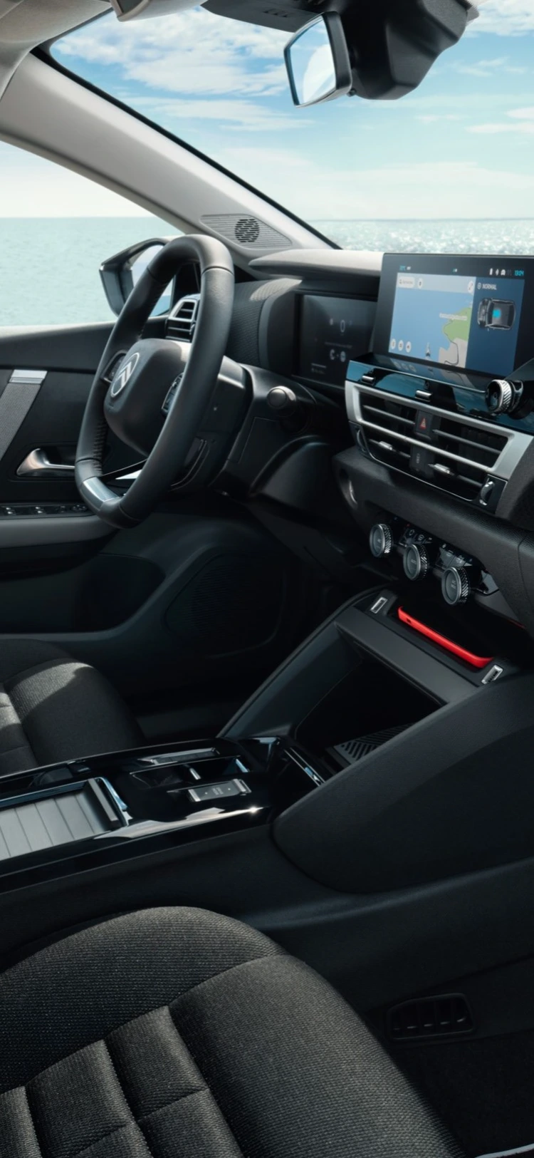 Vorderkabine des Citroën ë-C4 X zeigt Sitze, Armaturenbrett und Meerblick durch die Fenster