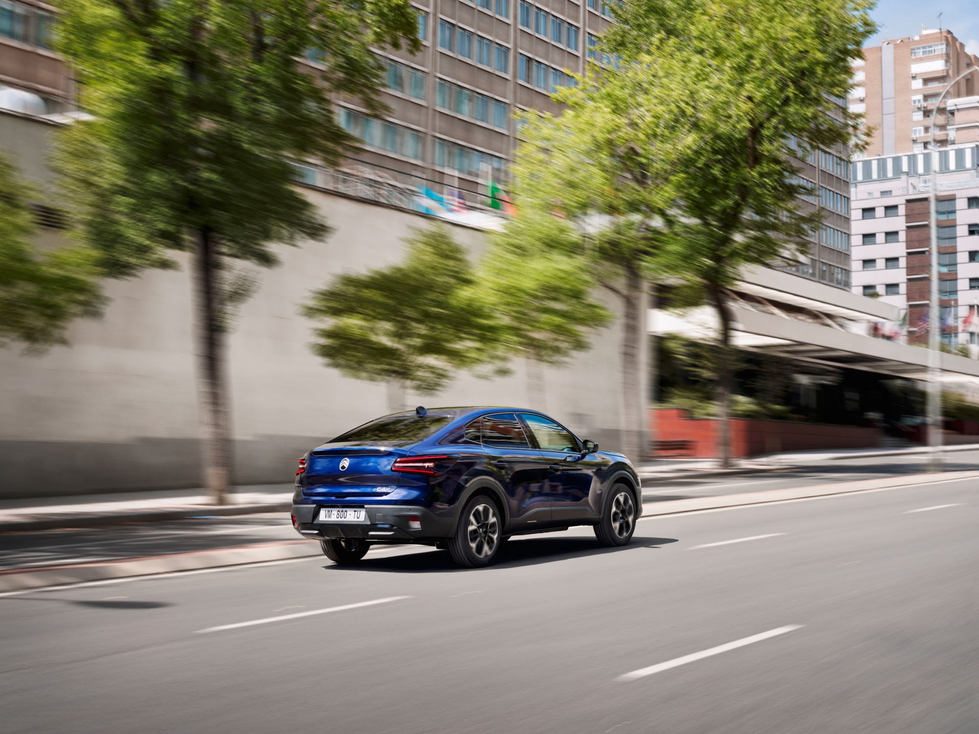 Dreiviertel-Heckansicht des fahrenden Citroën C4 X zeigt modernen Fastback-Stil für effiziente, erschwingliche Mobilität