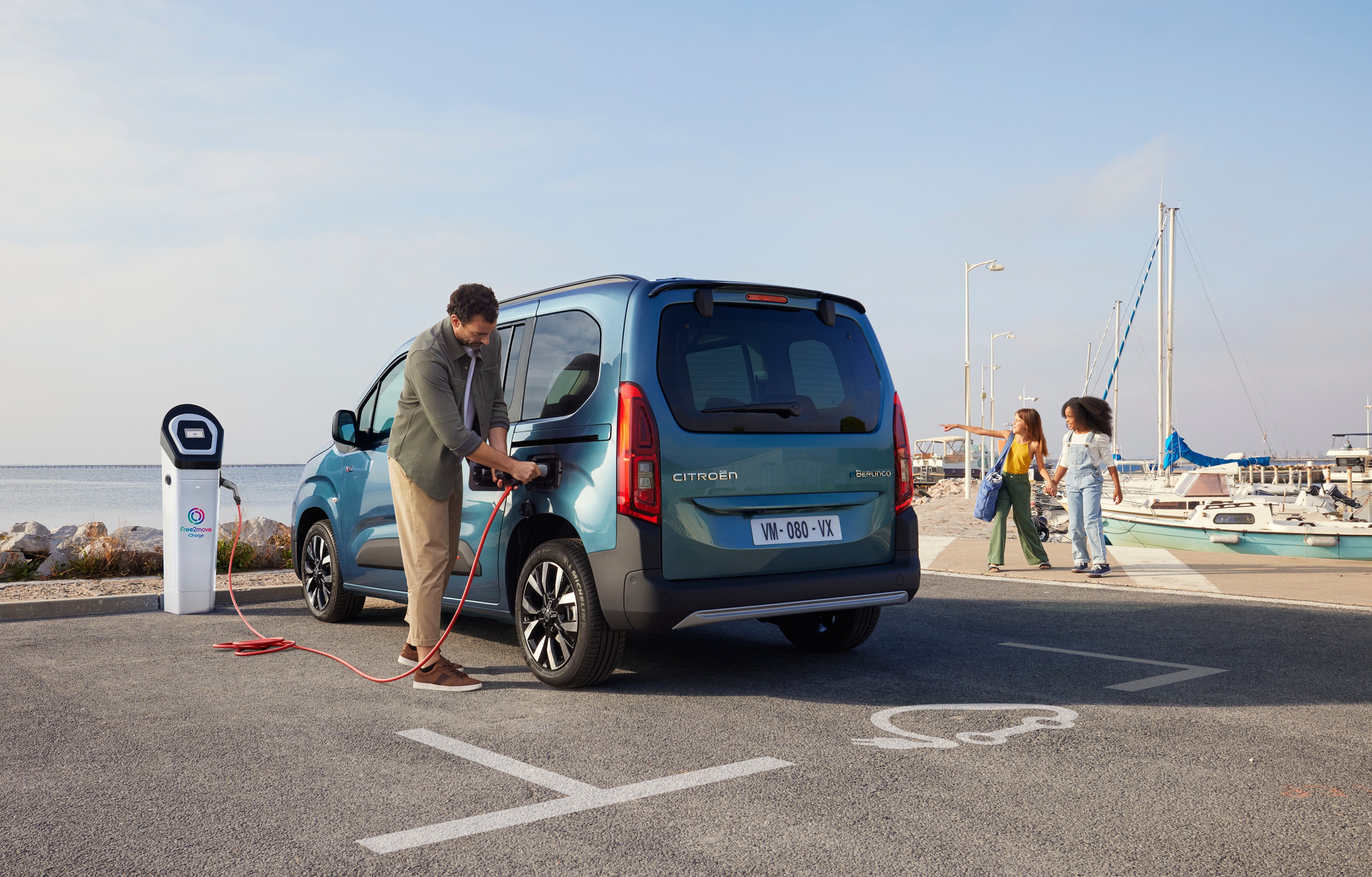 Rear three‑quarter view ë-Berlingo charging at a Free2move station showing safety, efficiency, technology and confident use